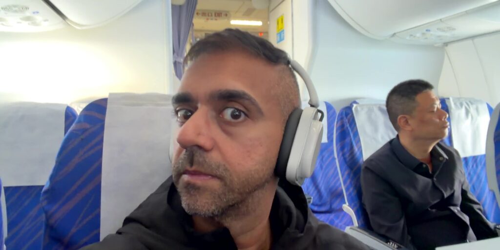 A lifestyle image of a passenger wearing the headphones during a flight, emphasizing comfort and travel portability.